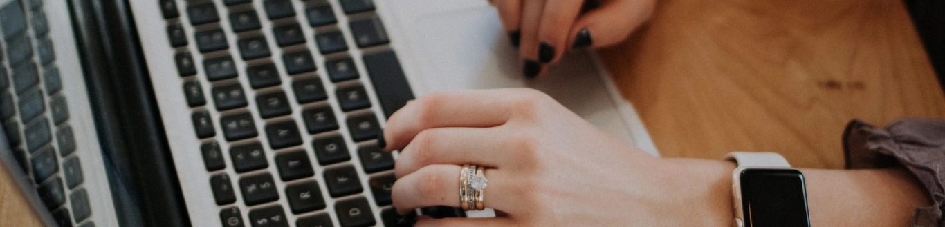 Hübsche Hände mit Ring und Uhr auf der Laptop Tastatur